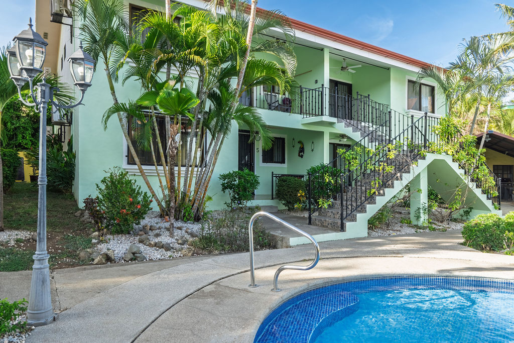 The mint green house at golden light, iron stairs beside the pool