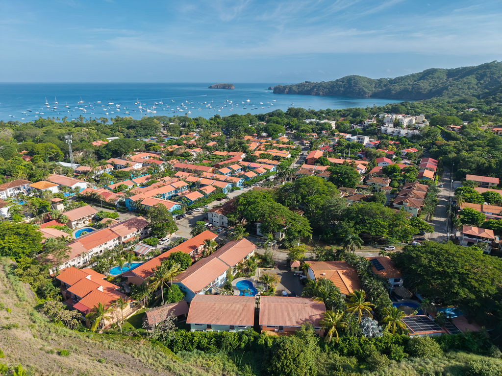 Aerial over red tile roofs to Coco Bay full of sailboats